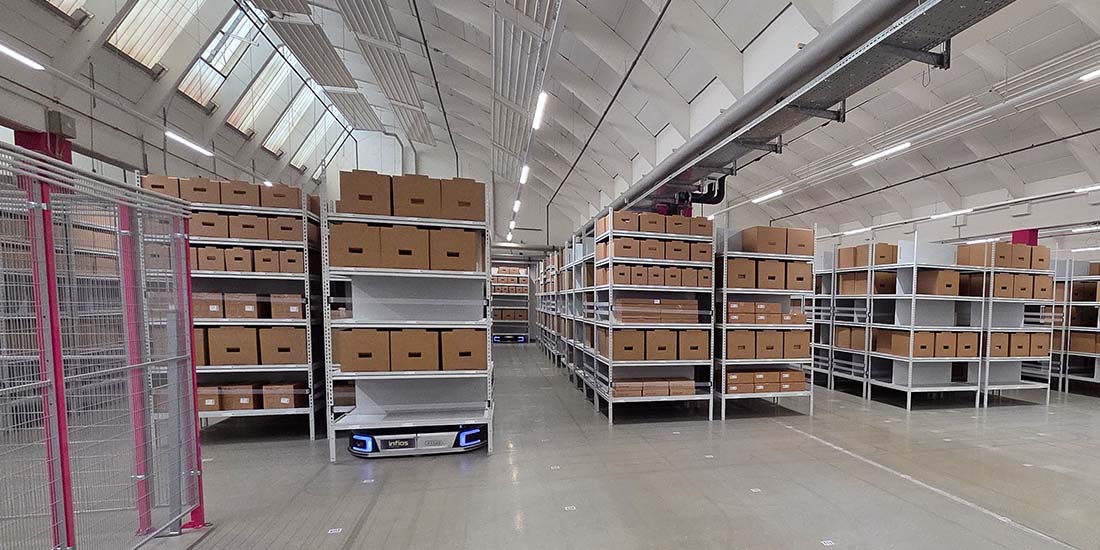 referenz_telekom_1100x550 Ein autonomer mobiler Roboter transportiert ein Regal zu einem Kommissionierarbeitsplatz.